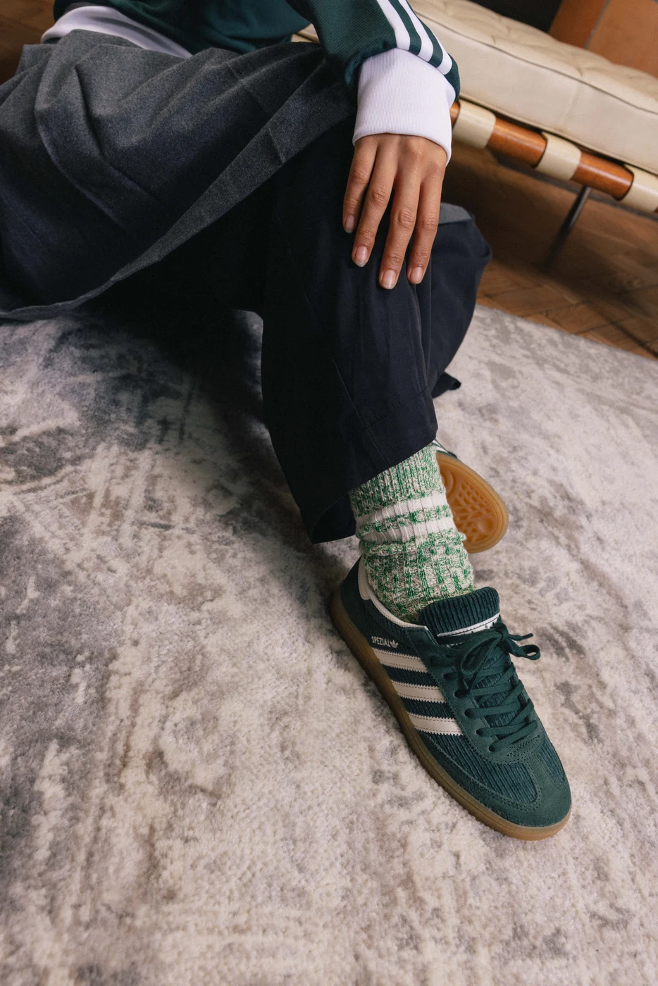 Green adidas footwear with grey socks against a textured rug